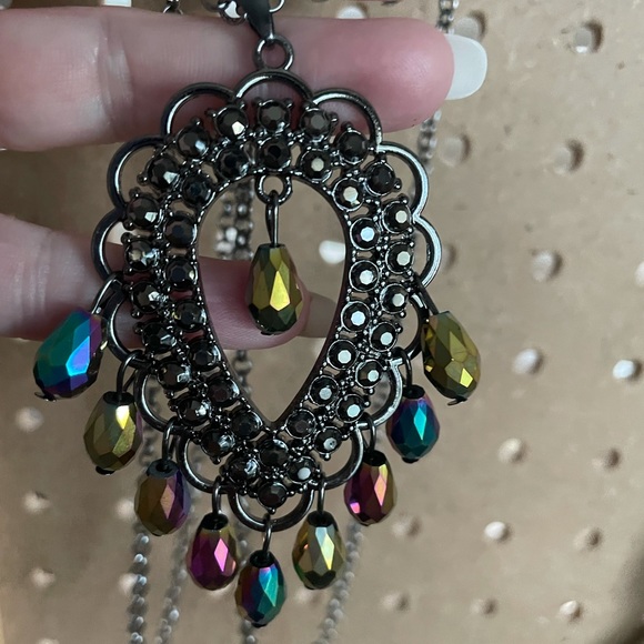Long silver necklace with brooch type drop accented by oil spill beads.